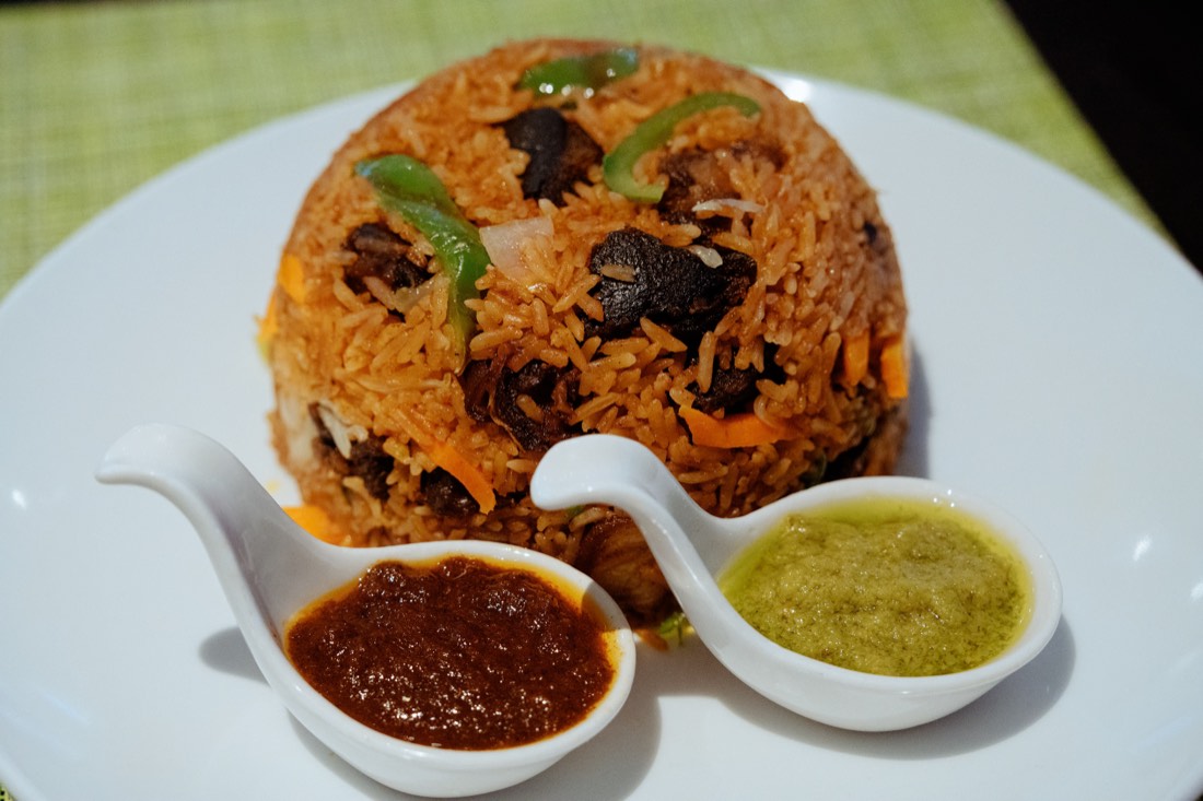 Jollof rice with beef and green peppers, served with shito and green pepper sauce