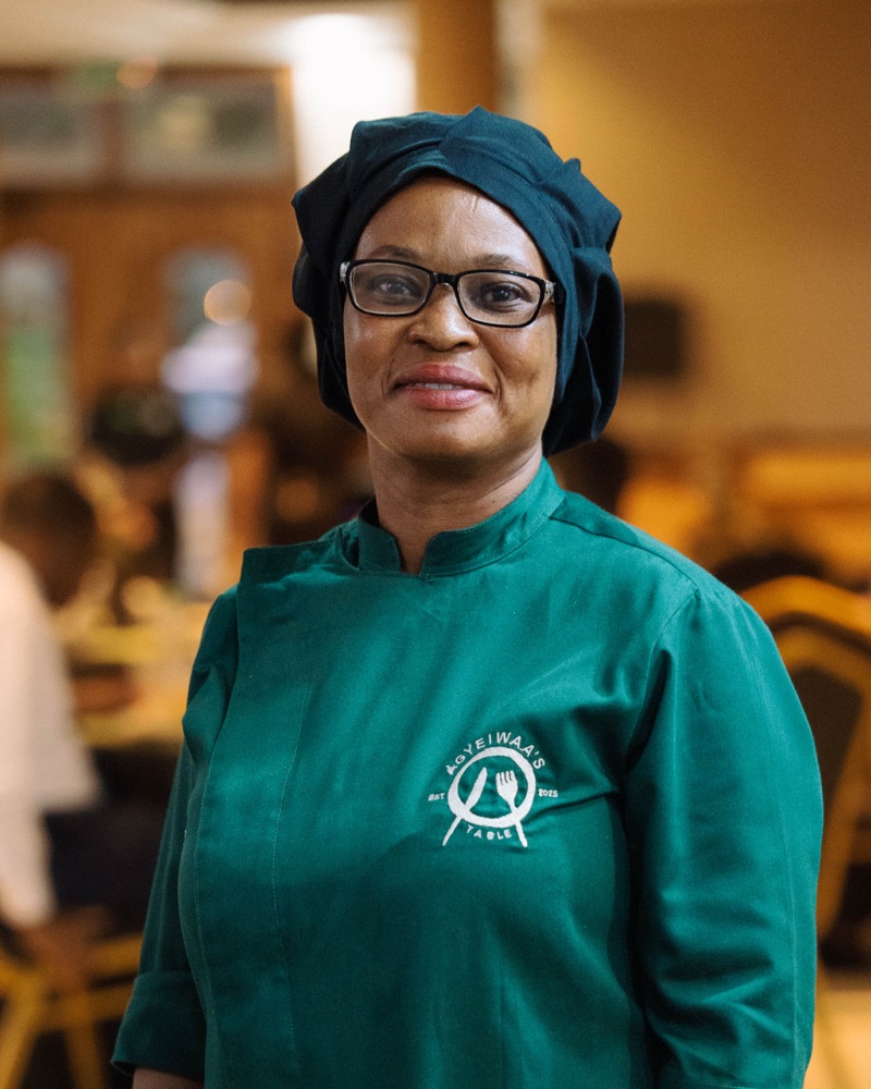 Agyeiwaa in her chef's tunic, standing in the dining room